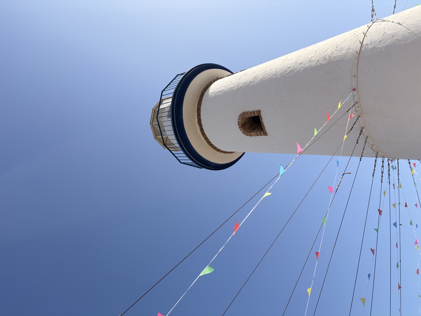 A white lighthouse rising against a deep blue sky.