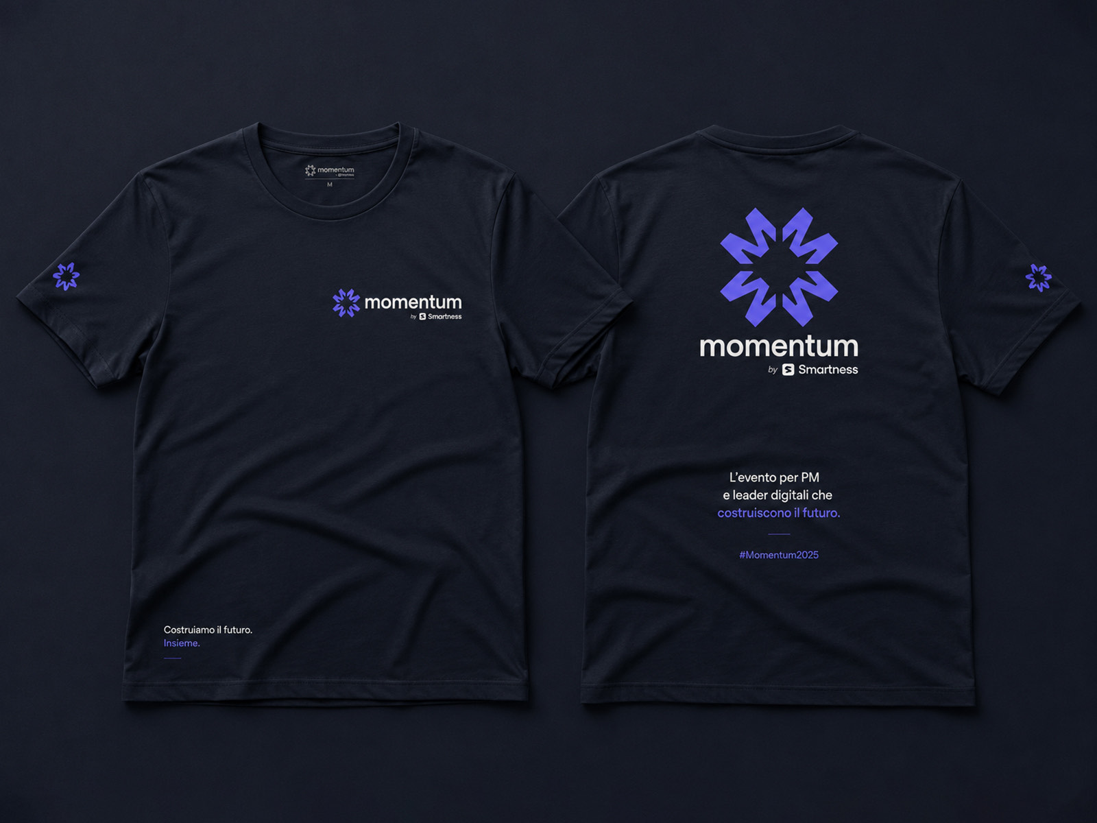 A navy Momentum t-shirt shown front and back, with a small chest lockup, a sleeve mark, and a large radial symbol and wordmark across the back above the event line and hashtag.